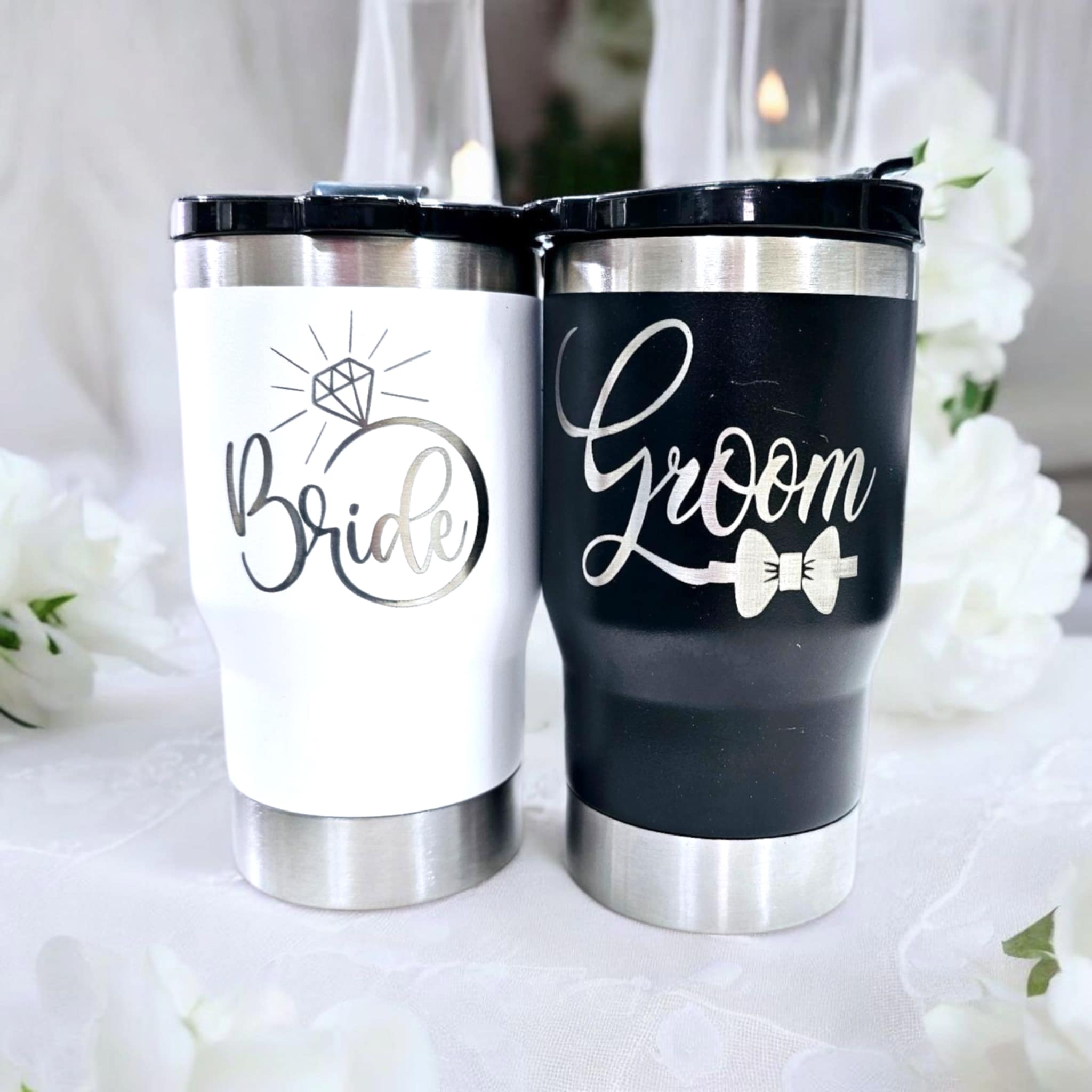 Laser engraved white 20 oz. tumbler with “Bride” design and a black 20 oz. tumbler with “Groom” design.